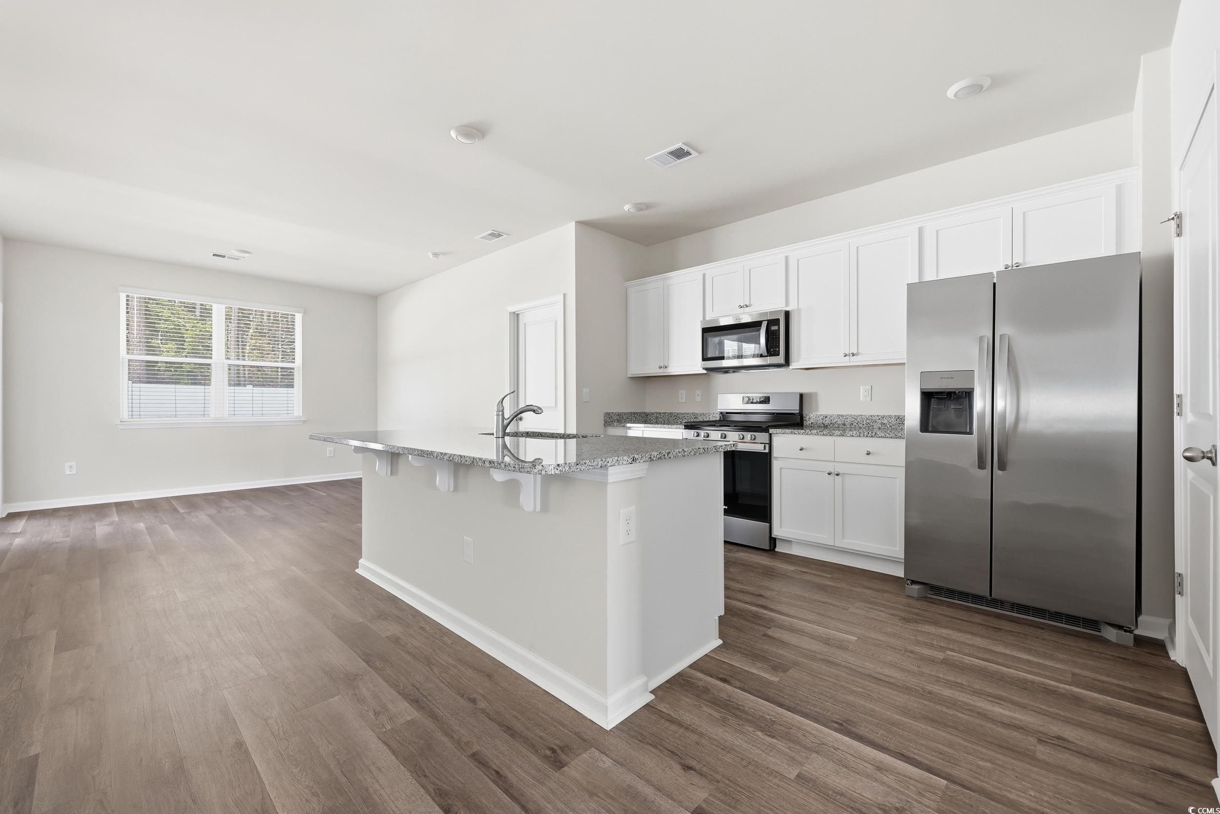 270 Columbus Street Conway, SC 29526 - Photo 11 of 38 Kitchen featuring stainless steel appliances, white cabinets, light stone countertops, a center island with sink, and dark wood-type flooring