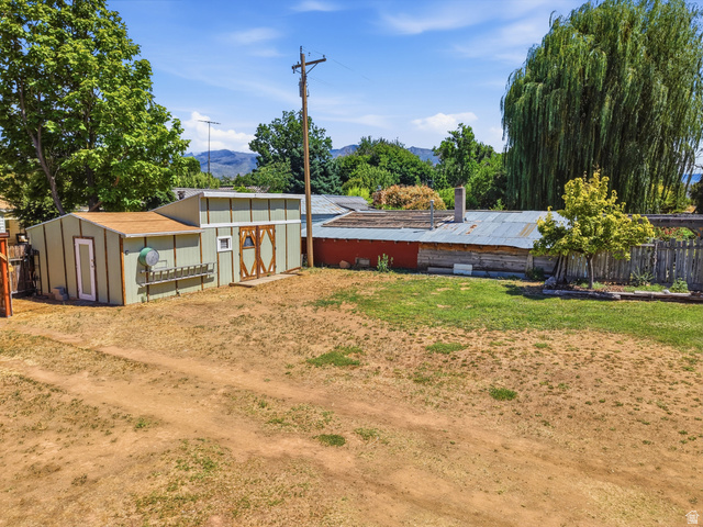 365 North Main Street Fillmore, UT 84631 - Photo 4 of 51 Expansive outdoor space featuring a detached storage shed with double barn doors, a fenced perimeter, mature trees, and mountainous terrain in the distant background