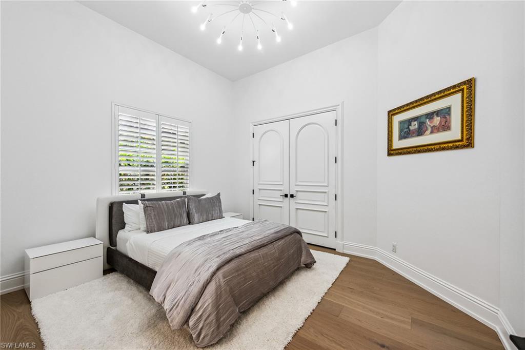 538 Riviera Drive Naples, FL 34103 - Photo 18 of 25 a spacious bedroom with a bed and a painting on the wall
