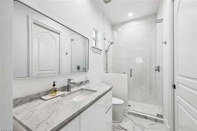 a bathroom with a granite countertop sink toilet and shower glass cabinet