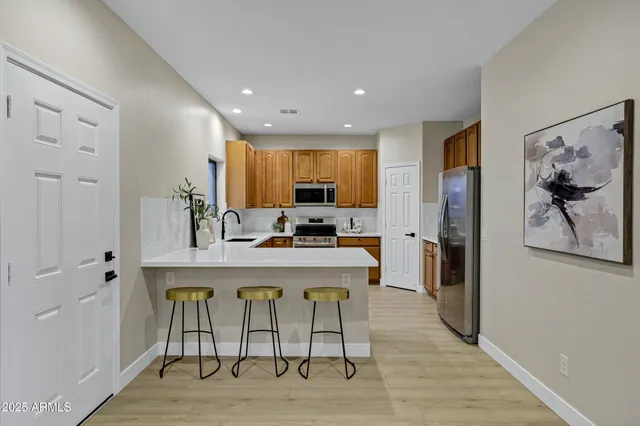 a view of a kitchen with kitchen island granite countertop wooden floor and refrigerator