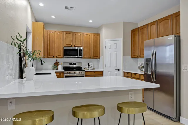 a kitchen with stainless steel appliances a table chairs in it and wooden floors