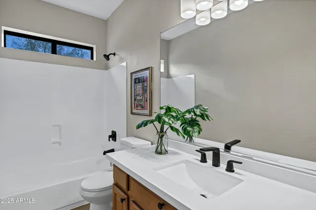 a bathroom with a sink vanity granite toilet and a mirror
