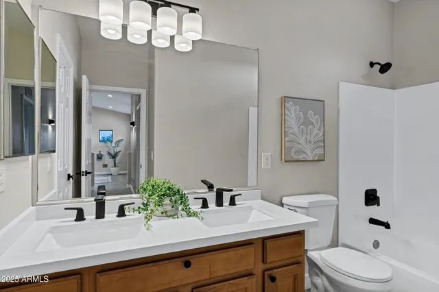 a bathroom with a sink a toilet a mirror and shower