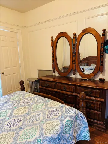 a bedroom with a bed a dresser and a wooden floor