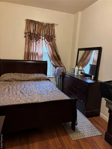 a bed sitting in a bedroom next to a window with wooden floor