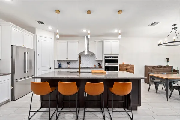a kitchen with granite countertop a counter space chairs stainless steel appliances and cabinets