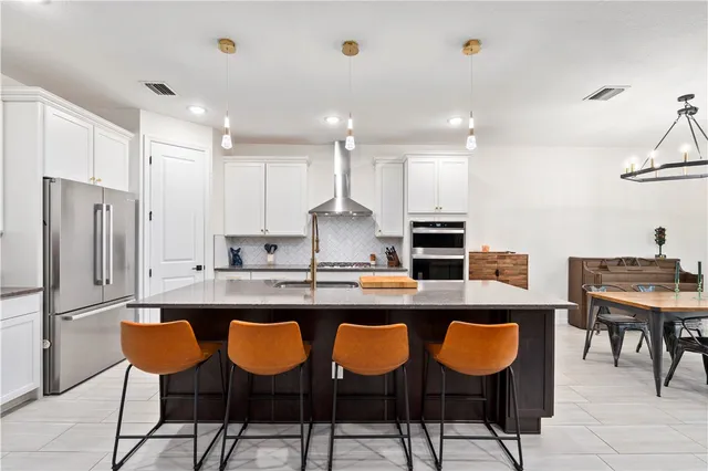 a kitchen with granite countertop a counter space chairs stainless steel appliances and cabinets