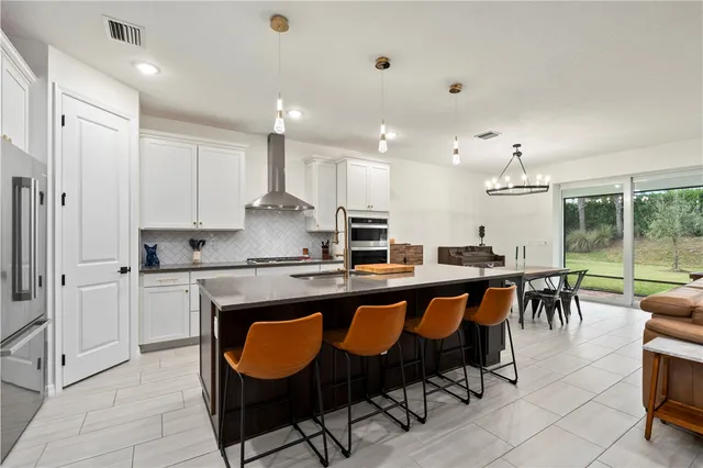 a kitchen with cabinets a sink dishwasher a dining table and chairs with wooden floor