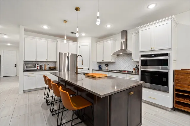 a kitchen with stainless steel appliances granite countertop a table chairs stove and refrigerator