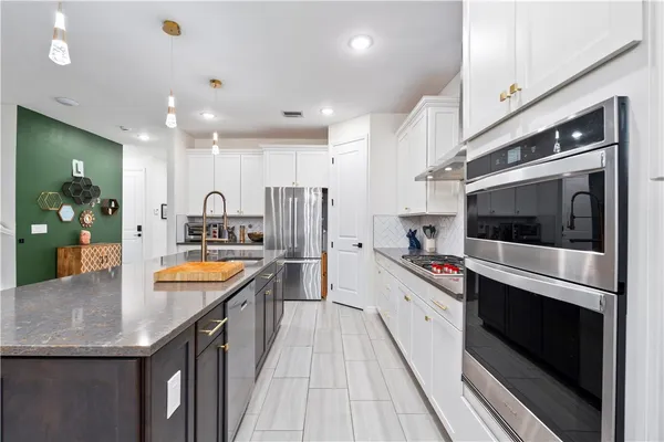 a large kitchen with stainless steel appliances granite countertop a lot of counter space and wooden floor
