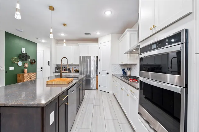 a large kitchen with stainless steel appliances granite countertop a lot of counter space and wooden floor