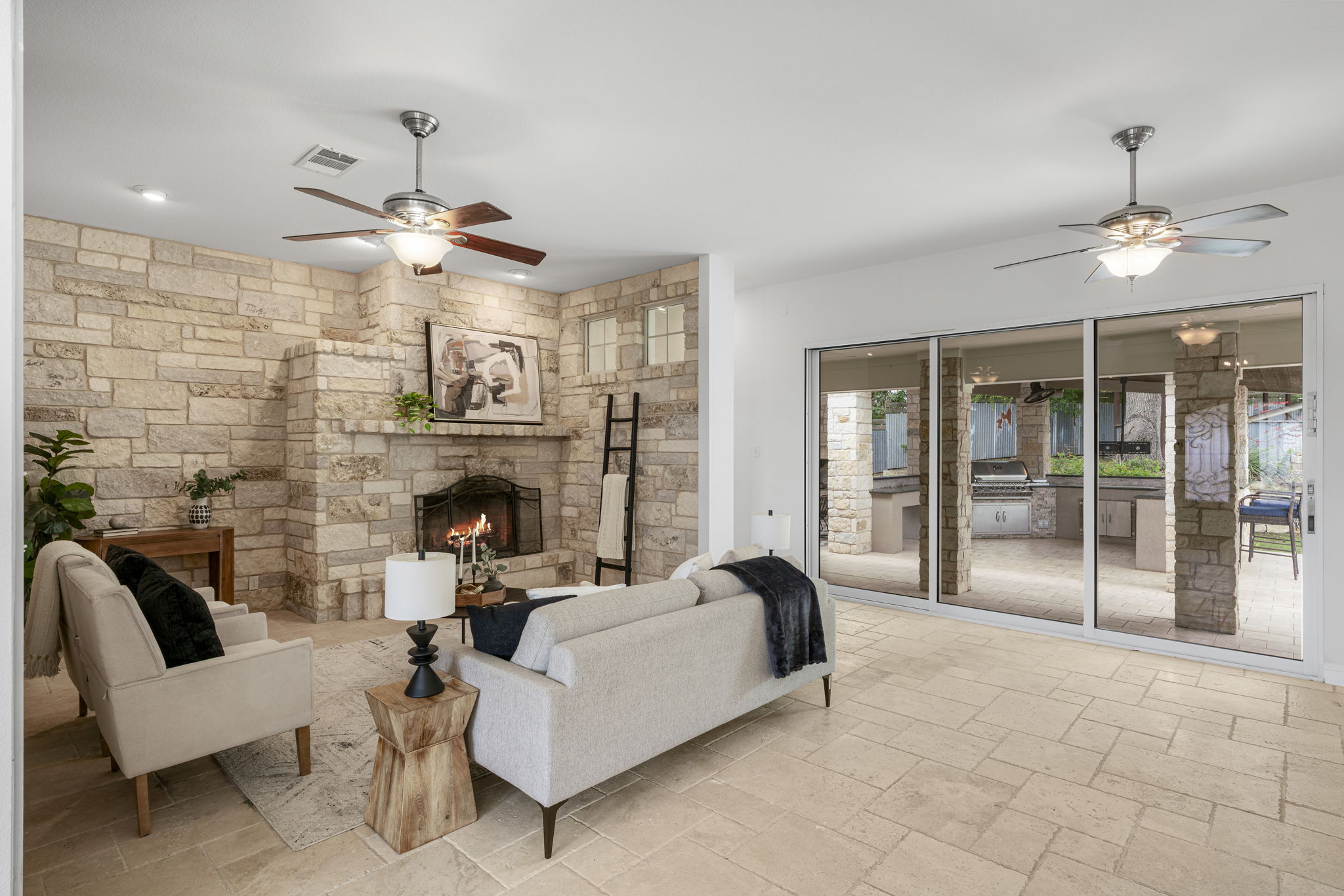 1129 Cedar Pass Road Driftwood, TX 78619 - Photo 6 of 40 Look out through these sliding glass doors straight to the outdoor kitchen. The travertine floors run throughout, keeping everything feeling cohesive.