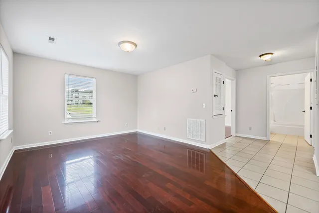 an empty room with wooden floor and windows