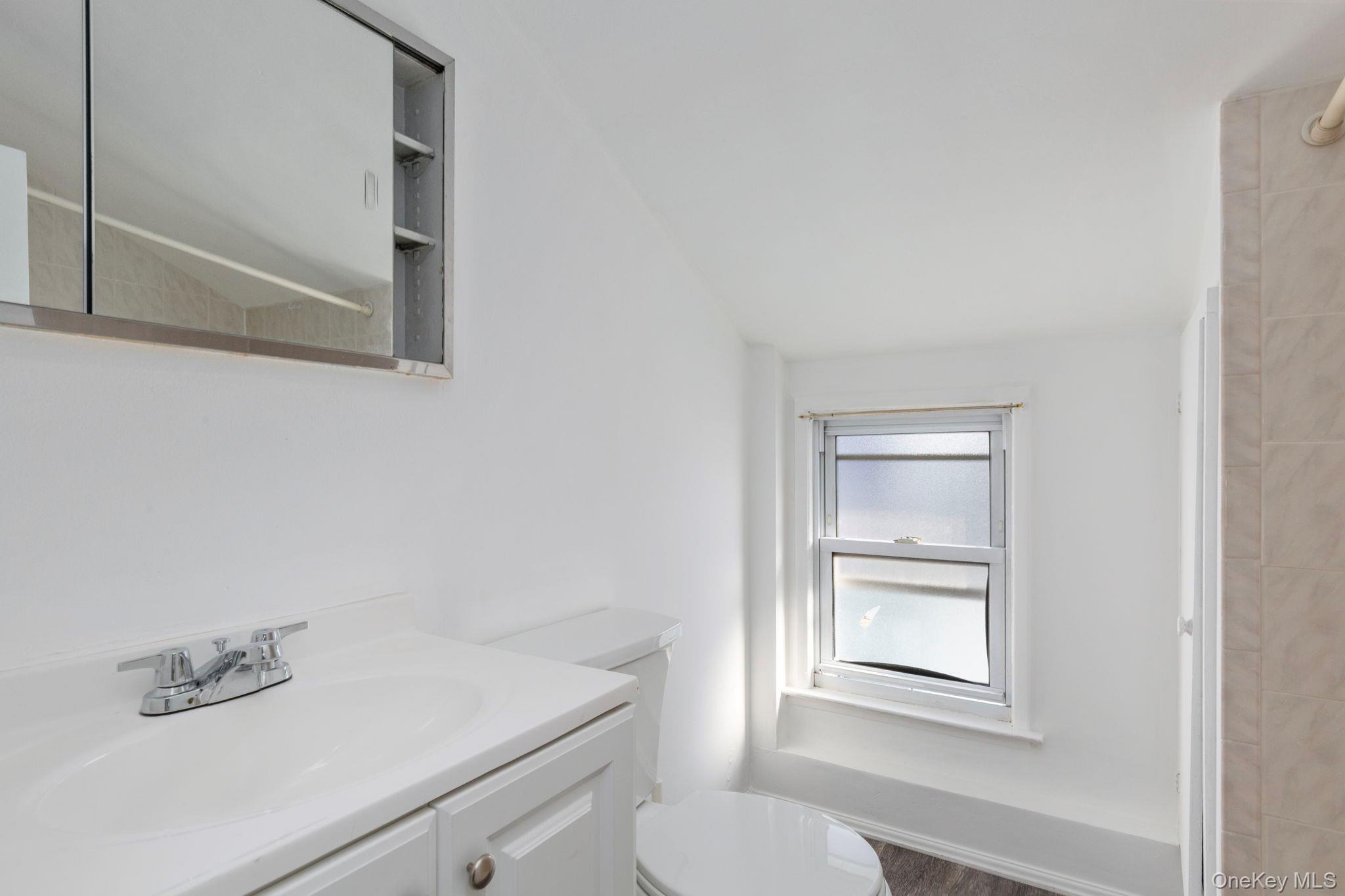92-69 220th Street Queens, NY 11428 - Photo 22 of 33 a bathroom with a toilet a sink and mirror