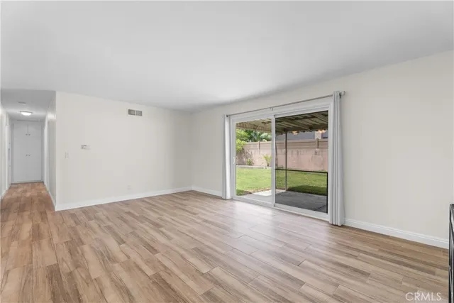 a view of an empty room with wooden floor and a ceiling fan