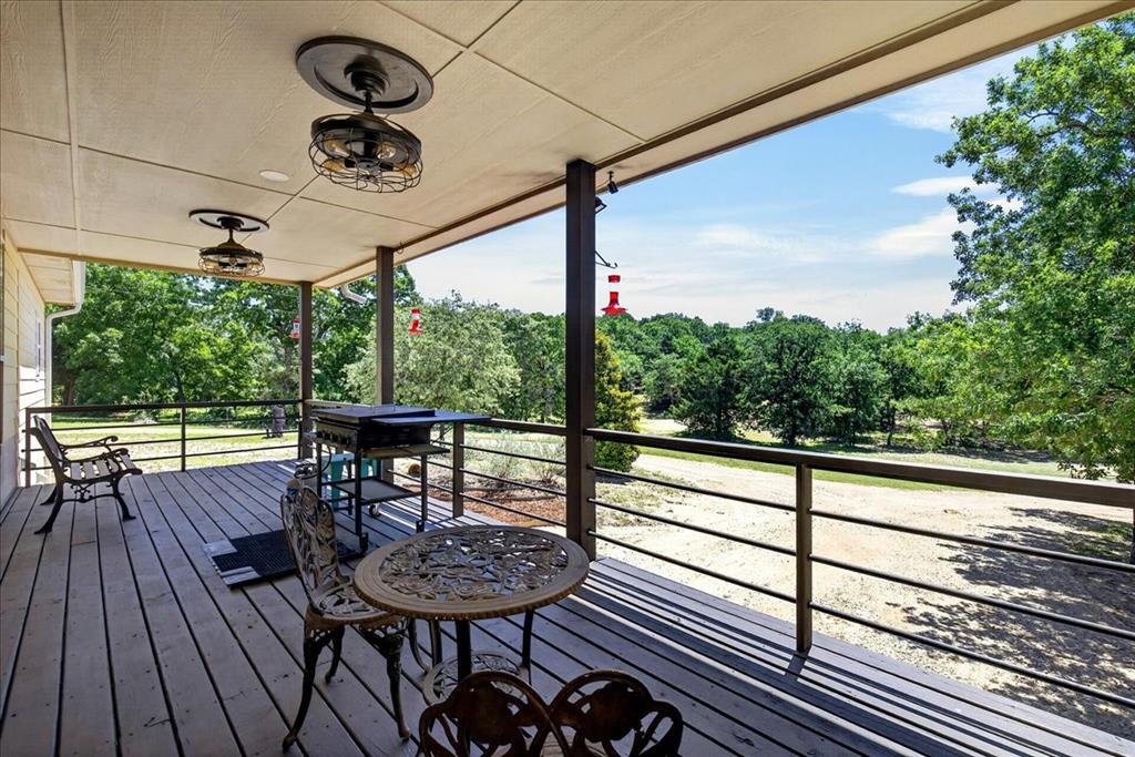11591 Farm To Market 59 Athens, TX 75751 - Photo 28 of 40 Spacious covered back porch featuring wood-finish decking, dark metal railings, and two industrial-style ceiling fans. So much space for family and friends to enjoy the peaceful serenity of country living.