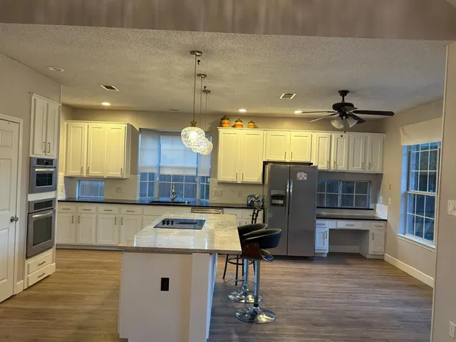 a kitchen with stainless steel appliances kitchen island a refrigerator and a wooden cabinets