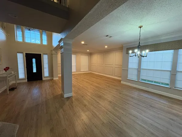 a view of a room with wooden floor chandelier and windows