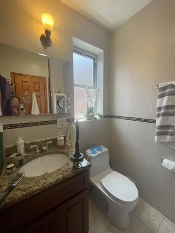 a bathroom with a granite countertop toilet sink and mirror