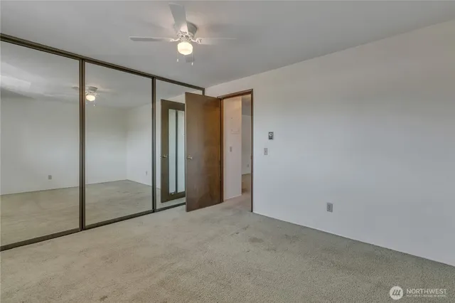 an empty room with closet and a chandelier fan