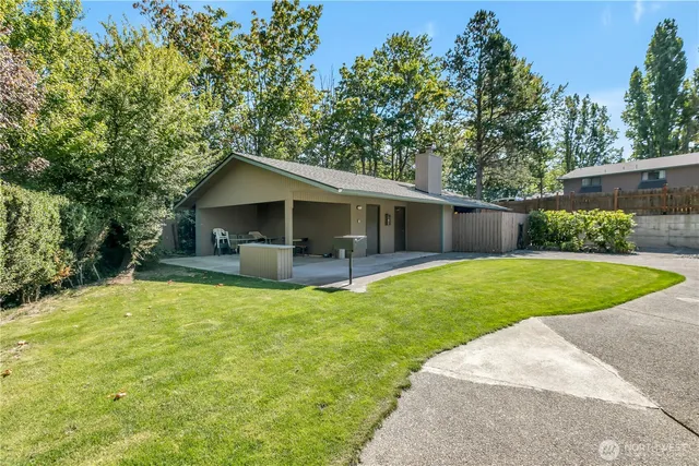 a view of a house with a yard patio and a tree