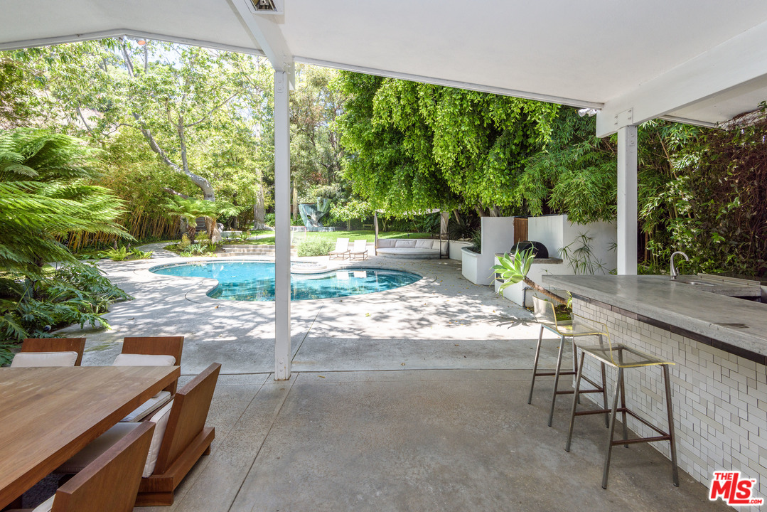 871 Leonard Road Los Angeles, CA 90049 - Photo 28 of 28 a view of a patio with table and chairs and couches with wooden floor