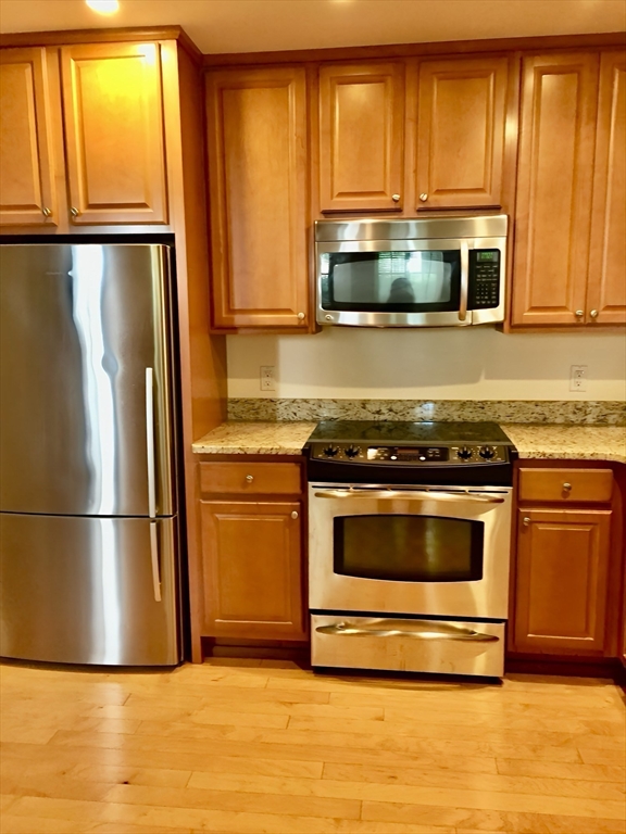 20 Chapel Street, Unit C308 Brookline, MA 02446 - Photo 7 of 15 a kitchen with granite countertop a refrigerator stove and microwave