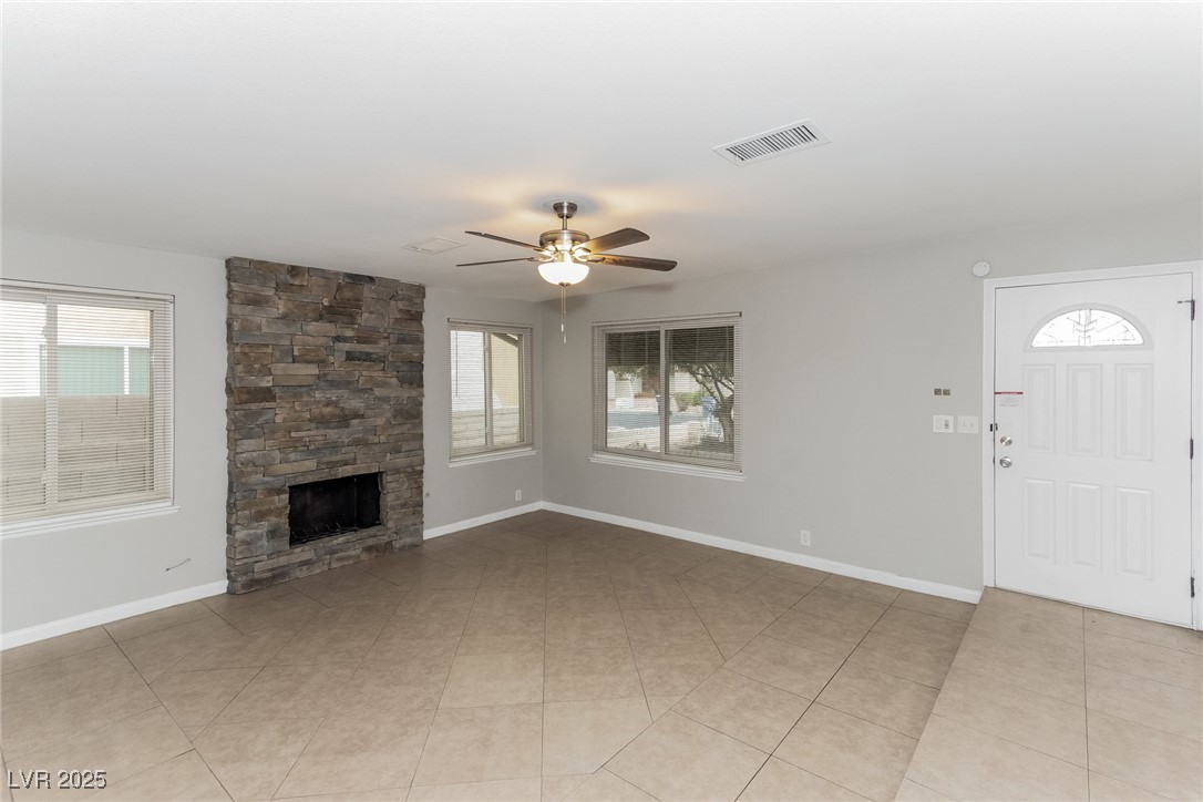 4737 Monaco Road Las Vegas, NV 89121 - Photo 9 of 21 Unfurnished living room with healthy amount of natural light, ceiling fan, a fireplace, and light tile patterned floors