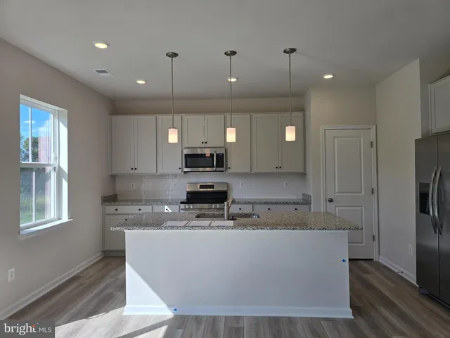 a large kitchen with stainless steel appliances kitchen island granite countertop a stove a sink a refrigerator and a microwave