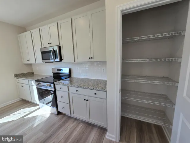 a kitchen with stainless steel appliances white cabinets and a wooden floor