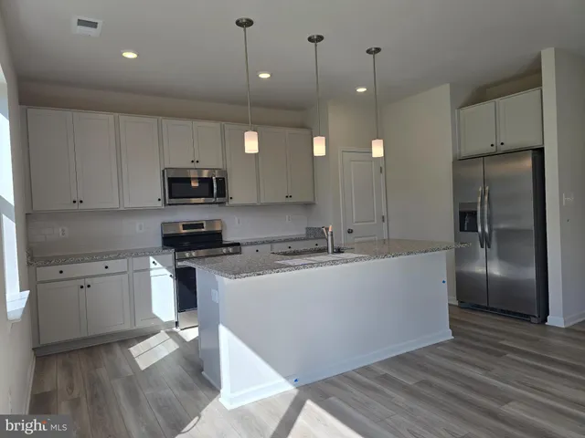 a large kitchen with cabinets wooden floor and stainless steel appliances