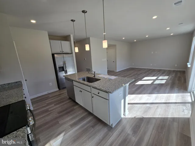 a kitchen with stainless steel appliances granite countertop a sink a island a stove and a wooden floors