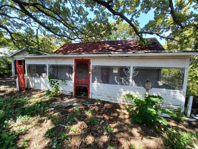 a view of a house with a small yard and a large tree