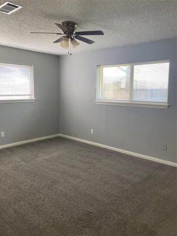 an empty room with a window and a fan