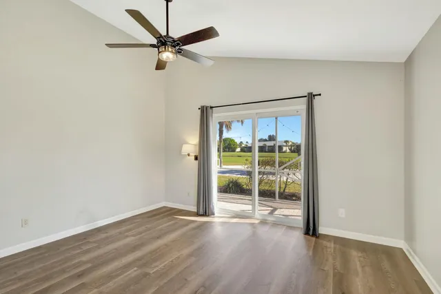 an empty room with wooden floor ceiling fan and windows