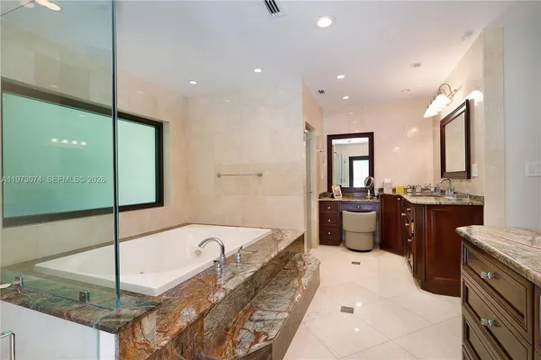 a large bathroom with a tub sink and mirror
