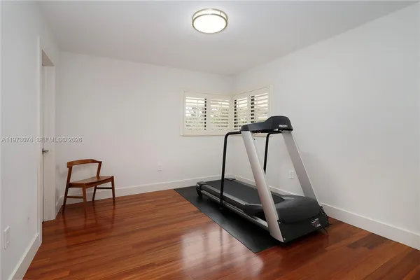 a room with gym equipment and wooden floor