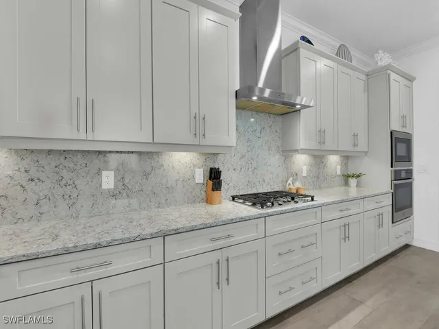 a kitchen with stainless steel appliances granite countertop a sink a stove and a white cabinets