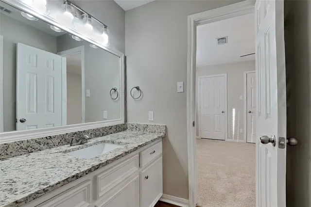 a bathroom with a granite countertop sink and a mirror