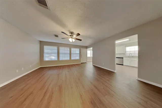 a view of an empty room with wooden floor and a window