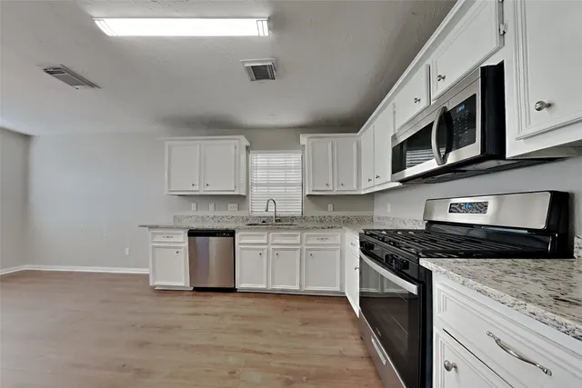 a kitchen with stainless steel appliances granite countertop a stove top oven a sink dishwasher and a microwave oven on the blue kitchen countertops
