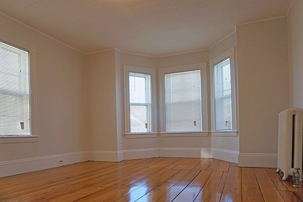 141 Brown Street, Unit 2F Waltham, MA 02453 - Photo 5 of 8 an empty room with wooden floor and windows