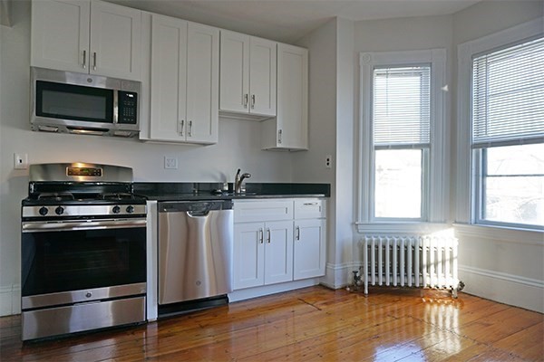 141 Brown Street, Unit 2F Waltham, MA 02453 - Photo 6 of 8 a kitchen with stainless steel appliances a stove a microwave oven cabinets and a window