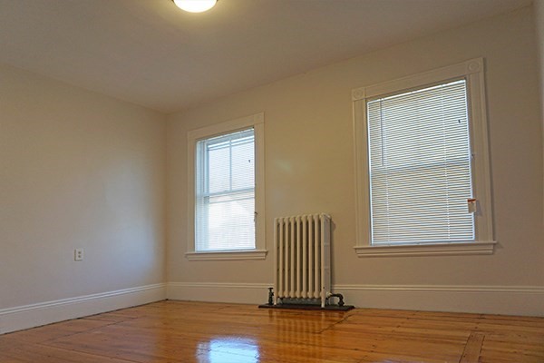 141 Brown Street, Unit 2F Waltham, MA 02453 - Photo 7 of 8 an empty room with wooden floor and windows