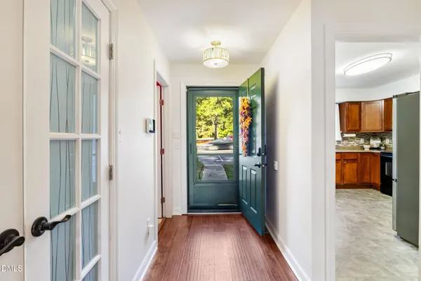 a view of a hallway with wooden floor and a kitchen