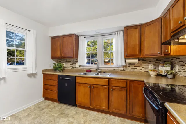 an empty room with wooden floor chandelier fan and windows