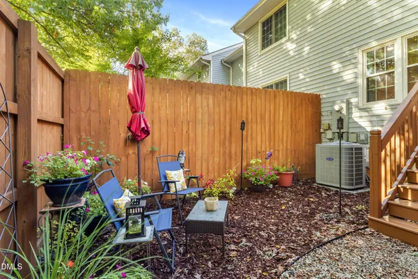 a patio with table and chairs and potted plants with wooden walls
