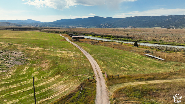 750 South Big Road Soda Springs, ID 83276 - Photo 8 of 40 Expansive rural property featuring a winding dirt road, green pastureland, a river, and distant mountains