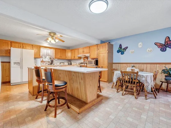 a dining hall with stainless steel appliances kitchen island granite countertop a table and chairs in it